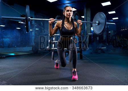 Front View Of Brunette Female Bodybuilder With Braids Doing Squats, Holding Barbell On Shoulders. Sr