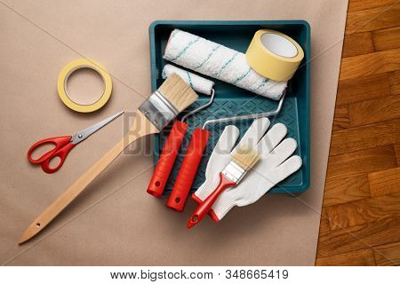 Tools needed to paint a wall: paint rollers and tray, brush and long-handled paint brush, masking tape, gloves, scissors