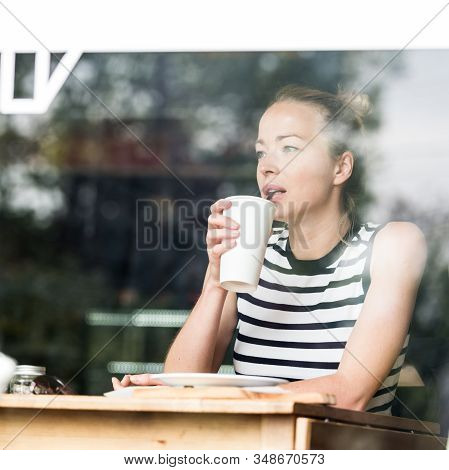 Young Caucasian Woman Sitting Alone In Coffee Shop Thoughtfully Leaning On Her Hand, Looking Trough 