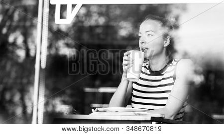 Young Caucasian Woman Sitting Alone In Coffee Shop Thoughtfully Leaning On Her Hand, Looking Trough 