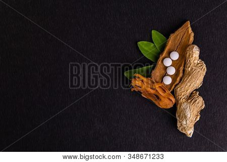 Close-up Of Cinnamon, Dry Ginger, Mace(javitri) And Ayurvedic Medicine With Green Leaves On Black Ba