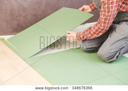 worker laying laminate floor underlayer padding
