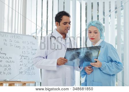 Chief Doctor And Surgeon Discussing Chest X-ray Of Patient Suspected Of Being Infected By Corona Vir