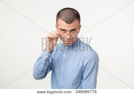 Doubtful Young Hispanic Man Looking With Disbelief Expression Through Glasses.