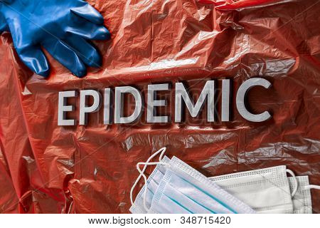 The Word Epidemic Laid By Metal Letters On Crumpled Red Pastic With Face Masks And Blue Protective G