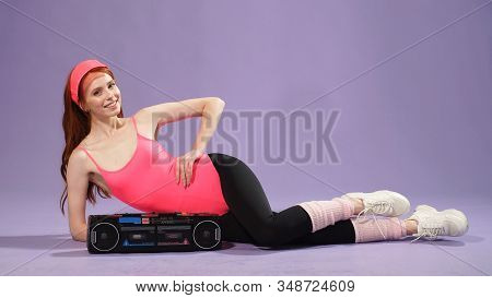 Woman With Freckles Is Wearing Comfortable Sportswear In The Style Of The 80s, Listening To Music On