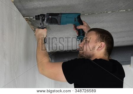 Builder Makes A Hole In A Concrete Wall With Hammer Drill