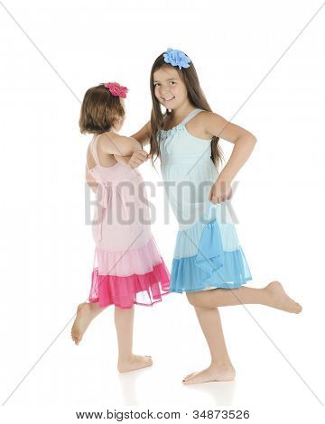 Dwa boso elementarnych dziewczęta frolicking z siebie.  Oni na sobie stroje identyczne, z wyjątkiem 