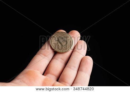 Bitcoin Coin In A Hand On A Black Background. Stock Photo Man Holding A Coin.