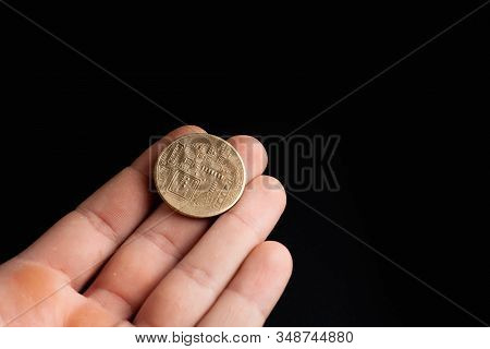Bitcoin Coin In A Hand On A Black Background. Stock Photo Man Holding A Coin.