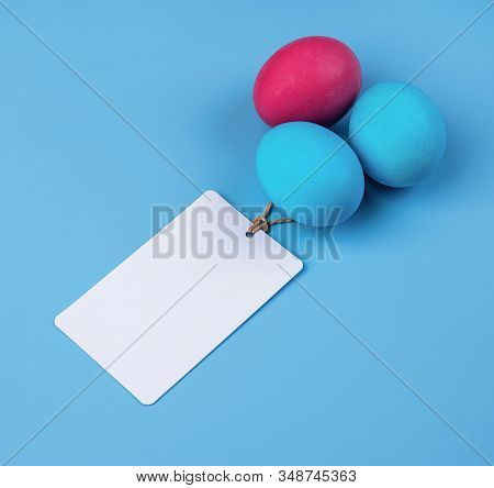 Easter Concept. Colored Eggs With Blank Tags Isolated On Blue Background With Copy Space