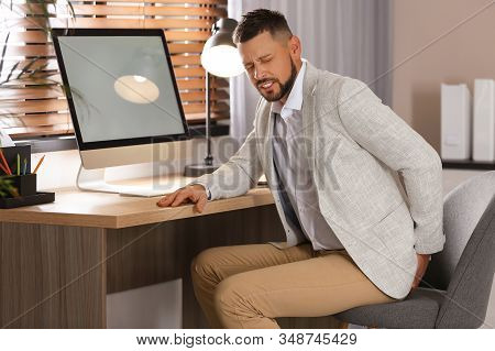 Man Suffering From Hemorrhoid At Workplace In Office