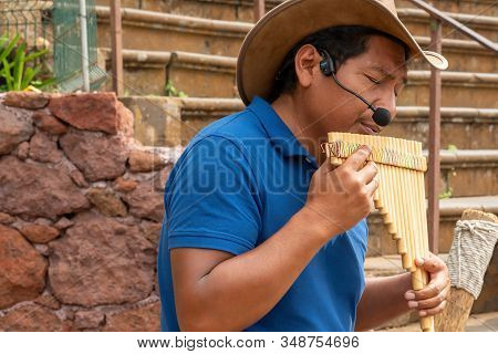 Madeira, Portugal, August 27, 2018: An Indian In A Hat Emotionally Plays A Multi-barrel Wooden Flute