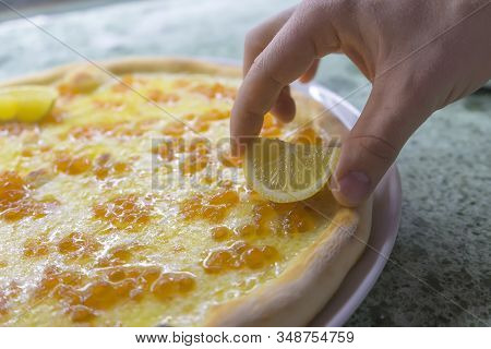 The Chef Puts A Slice Of Lemon In A Caviale Pizza With Mozzarella Cheese And Red Salmon Caviar.