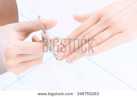 Closeup Of Female Hands Are Holding Scissors. Young Woman Is Cutting Her Nails, Making Herself Hygie