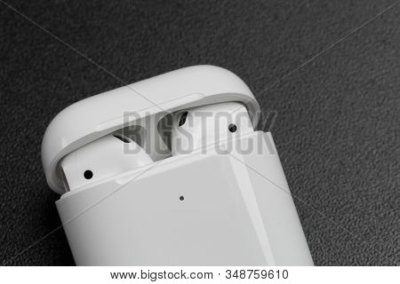 Air Pods With Wireless Charging Case. New Airpods 2019 On Black Background. Entangled 3.5 Headphones