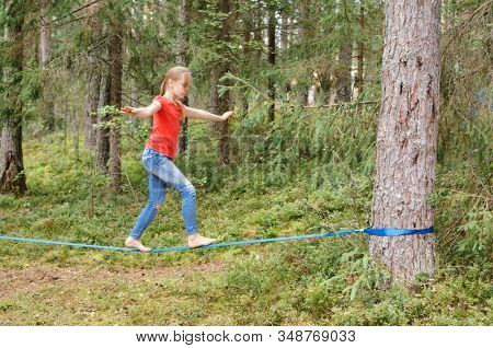 Tween girl balancing on slackline during summer holidays