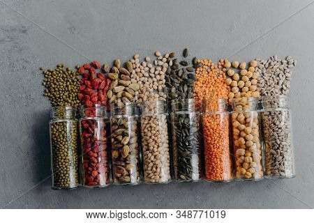 Spilled Organic Products In Glass Containers Isolated Over Grey Background. Vegetarian Diet Concept.