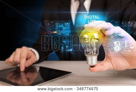 Businessman holding lightbulb with DIGITAL LIFE inscription, online security idea concept