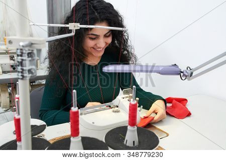 Young Tailor Using Professional Overlock Sewing Machine In Workshop Studio. Equipment For Edging, He