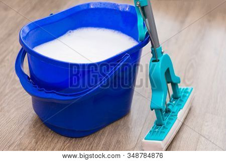 The Blue Bucket Of The Janitor Cleaner Is On The Floor Filled With Water And Detergent. Mop With A H