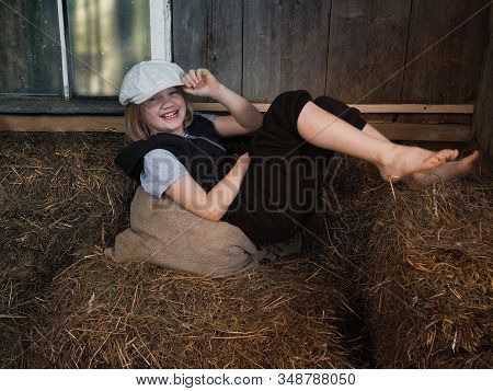 A Laughing Child In The Village In The Hayloft. Emotional Portrait.