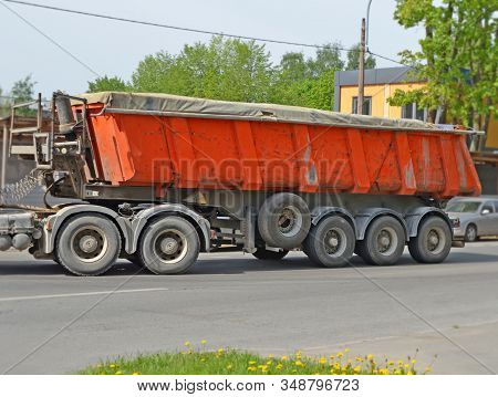 Dump Trailer Loaded With Loose Material Under Tent On City Street Near The Fence Of Construction Sit