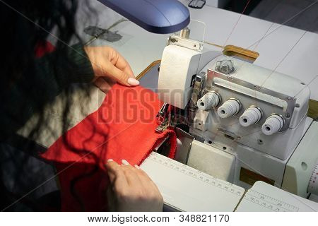 Young Tailor Using Professional Overlock Sewing Machine In Workshop Studio. Equipment For Edging, He