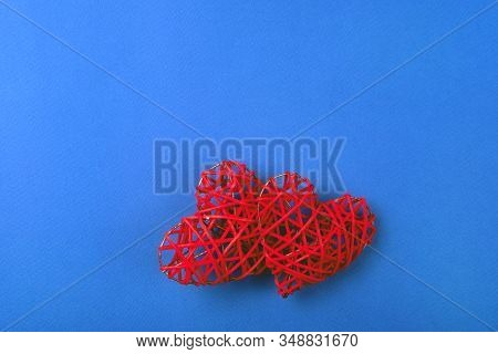 Two Beautiful Wicker Red Hearts On The Cornflowerblue Background. St Valentines Concept With Copy Sp