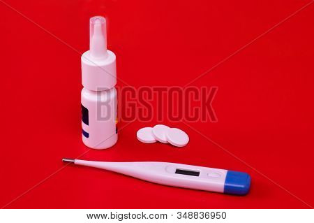 Electronic Thermometer, Spray And Pills On A Red Background. Means For Treating Flu And Colds, Lower