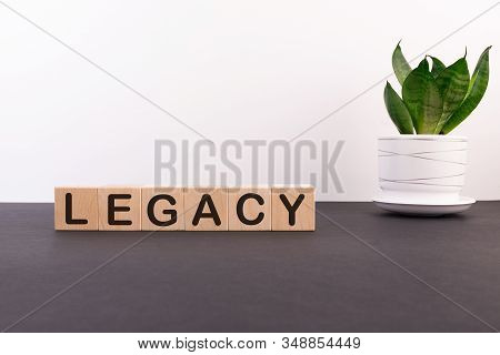 Legacy Word On Wooden Cubes On A Dark Table With A Flower And A Light Background