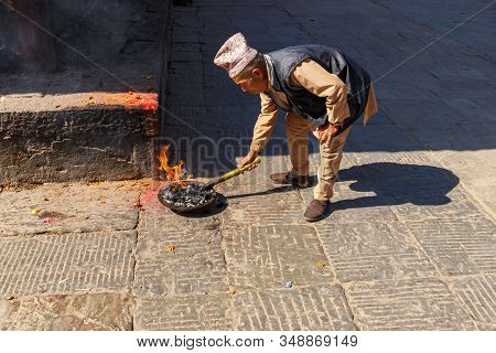 Kirtipur, Nepal - November 13, 2016: Nepali Man Kindles A Ritual Fire. Bagh Bhairab Temple.