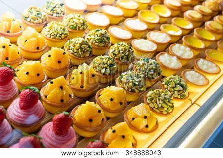 Various Flavors Of Fruit Mini Pie Desserts Being Displayed Inside A Transparent Glass Cabinet