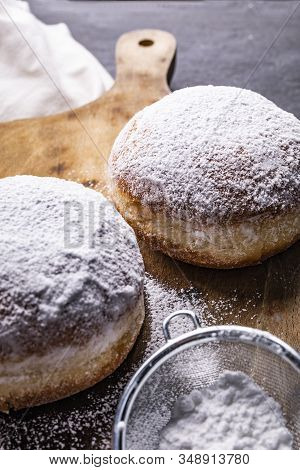 Donuts Covered With Powdered Sugar On The Wooden Cutting Board And Stony Worktop.