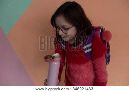 Girl With Cup. Schoolgirl Girl In Glasses Drinks Water From A Thermomug.a Schoolgirl Drinks Tea, Jui
