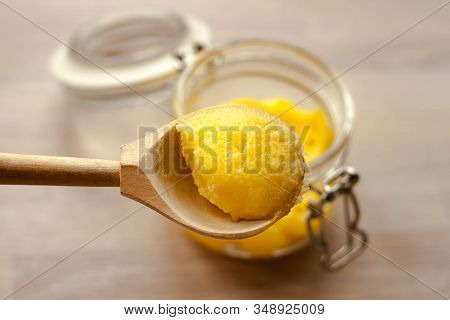 Ghee Clarified Butter Desi Yellow Color In Glass Jar With Spoon Made From Wood On Natural Wooden Bac
