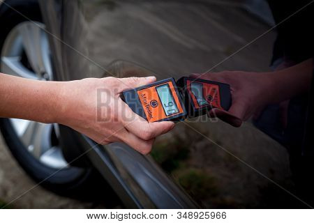 Measuring The Thickness Of The Car Paint Coating In Black Color Using A Paint Thickness Gauge.