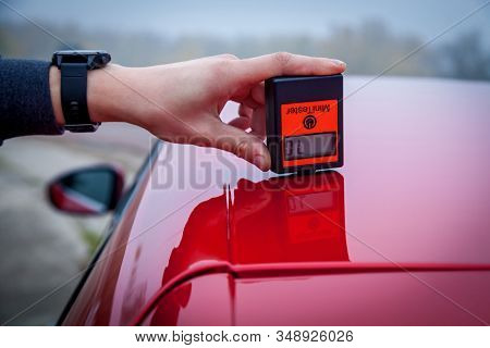 Measuring The Thickness Of The Car Paint Coating In Black Color Using A Paint Thickness Gauge.