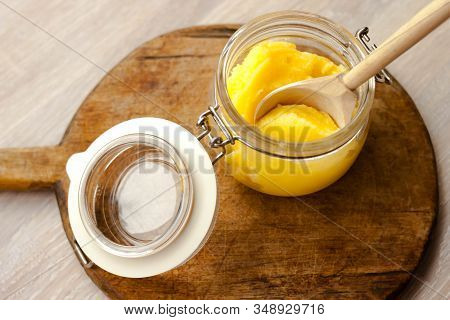 Ghee Clarified Butter Desi Yellow Color In Glass Jar With Spoon Made From Wood On Natural Wooden Bac