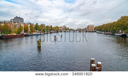 View On The River Amstel Filled With Small Boats.