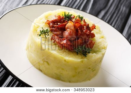 Mashed Potatoes And Green Cabbage Topped With Fried Bacon Closeup In A Plate. Horizontal