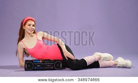 Woman With Freckles Is Wearing Comfortable Sportswear In The Style Of The 80s, Listening To Music On