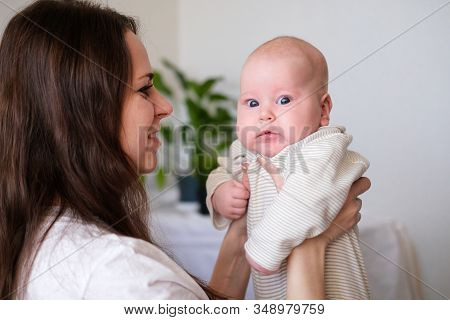 Happy Baby. Little Cutest Serious Caucasian White Infant Child Looking At Camera On Mother Hands. Fa