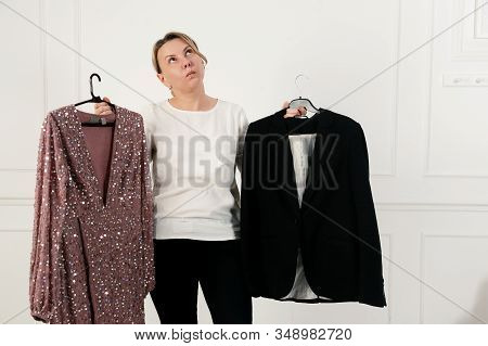 A Woman Has A Difficult Choice, Not Knowing What To Wear. Evening Dress Or Business Suit. Nothing To