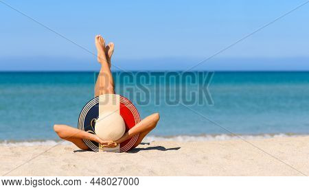 A Slender Tanned Girl On The Beach In A Straw Hat In The Colors Of The Flag Of France. The Concept O