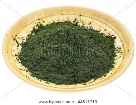 tigela pequena de pó de spirulina havaiano contra um fundo de madeira áspera celeiro pintado branco