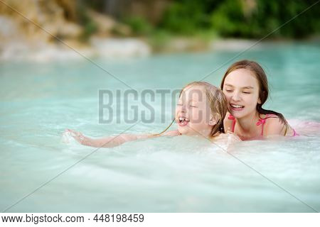 Two Young Sisters Bathing In Natural Swimming Pool In Bagno Vignoni, With Thermal Spring Water And W