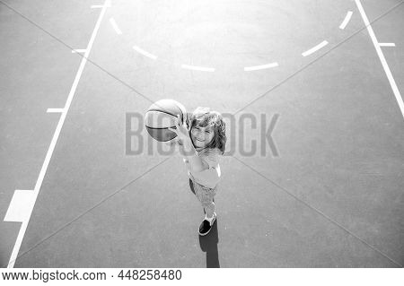 Kid Playing Basketball With Ball. Angle View From On Top Of Child Boy Preparing For Basket Ball Shoo