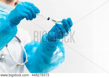 Young Woman Doctor In A Medical Mask And Gloves With A Syringe In Her Hand And A Stethoscope In A Ho