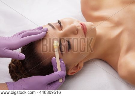 Beautician Is Removing Hair From Beautiful Female Face With Hot Wax. Woman Has A Beauty Treament Pro